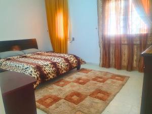 een slaapkamer met een bed met een tapijt en een raam bij Duplex Familial 2 Chambres 131m2 avec Jardin Privé - Service Aéroport - Internet Fibre Optique in Borj Turki