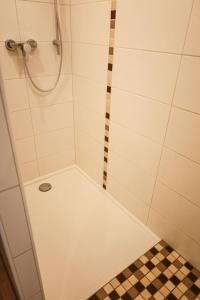 y baño con ducha y suelo de baldosa. en Ferienwohnung zum Alten Fachwerk en Melsungen