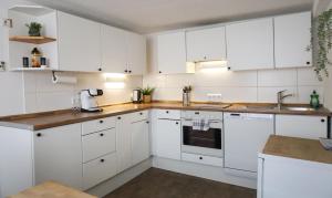 una cocina con armarios blancos y electrodomésticos blancos en Ferienwohnung zum Alten Fachwerk en Melsungen
