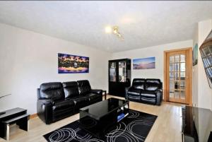 a living room with a black leather couch and a table at Sunny Cove Holiday Let in Aberdeen
