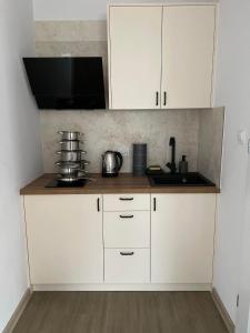 uma cozinha com armários brancos e uma bancada em Pokoje na Jaśminowej em Pisz