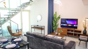 a living room with a couch and a television at Duplex 2BR Delight - Masdar City in Abu Dhabi