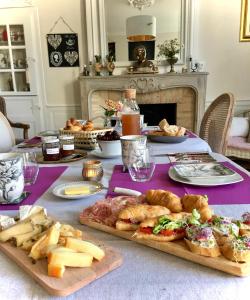 a table with cheese and bread and food on it at Au bord de l'étang - Le Presbytère in Montaigu