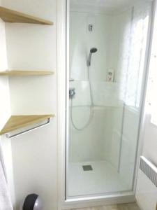 La salle de bains est pourvue d'une douche avec une porte en verre. dans l'établissement Camping, à Litteau