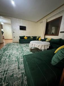 uma sala de estar com um sofá verde e uma mesa em appartement spacieux em Deroua