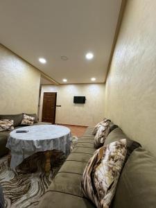 appartement spacieux في Deroua: غرفة معيشة مع أريكة وطاولة