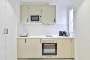 eine Küche mit weißen Schränken, einer Spüle und einer Mikrowelle in der Unterkunft Super appartement 4P 1BR Marché aux Puces in Saint-Ouen
