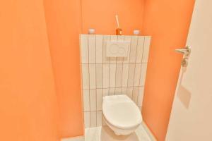 ein Badezimmer mit einem weißen WC in einer orangefarbenen Wand in der Unterkunft Super appartement 4P 1BR Marché aux Puces in Saint-Ouen