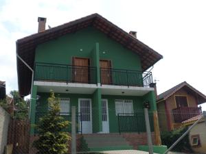 a green house with a balcony on top of it at chales e aptos Carvalhos em monte verde in Monte Verde