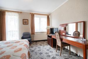 a hotel room with a desk and a bed at Ośrodek Wczasowy Marevita in Dziwnówek