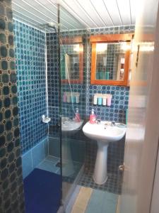 y baño de azulejos azules con lavabo y ducha. en Casa Sol e Mar, en Colares