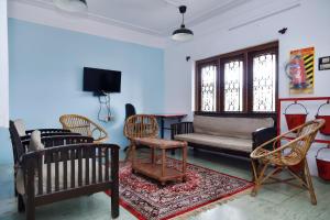 a living room with chairs and a couch and a tv at HIlltop Cottage Homestay in Ooty