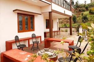 a patio with tables and chairs in front of a house at HIlltop Cottage Homestay in Ooty