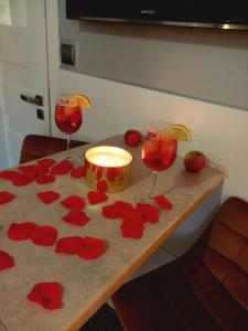 Dois copos de vinho e uma vela numa mesa com flores vermelhas. em Zielony Zakątek em Koszalin