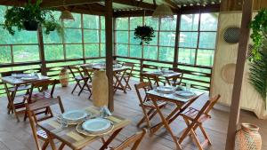 um restaurante com mesas e cadeiras de madeira e janelas em Bioma EcoLodge em Iranduba