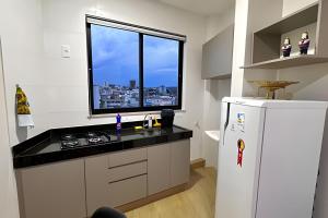 a kitchen with a white refrigerator and a window at Portofino Apart Hotel Praça do Mercado in Divinópolis