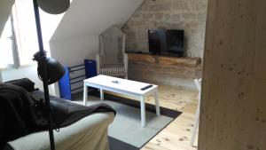 a living room with a white table and a tv at Studio meublé proche conseil départemental du Jura in Lons-le-Saunier