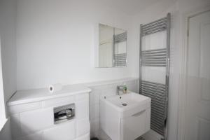 Baño blanco con lavabo y espejo en Exceptionally Stunning Four Bed Terraced House With Two Bathrooms- Recently Renovated en Spon End
