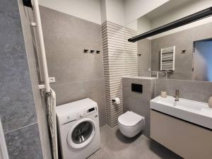 a bathroom with a washing machine and a sink at Apartament na wydmie in Mrzeżyno