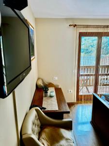 a living room with a couch and a television on a wall at Hotel Alpine in Log pod Mangartom