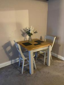 a dining room table with a vase of flowers on it at Rustic Retreat cottage in Thirsk