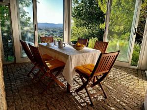 uma sala de jantar com mesa, cadeiras e janelas em Casa da Fontiña em Tortoreos