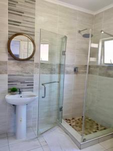 a bathroom with a glass shower and a sink at House At Eight in Jwaneng