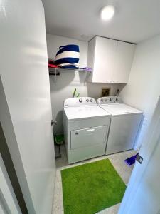 a laundry room with a washing machine and a green rug at Modern Beachside Bliss: 2 Bed/2 Bath Condo Haven in Rehoboth Beach