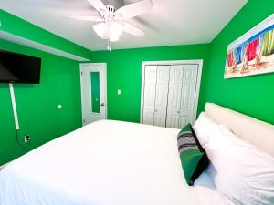a green bedroom with a white bed and a ceiling fan at Modern Beachside Bliss: 2 Bed/2 Bath Condo Haven in Rehoboth Beach