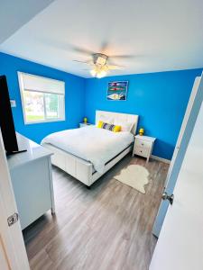 a blue bedroom with a bed and a ceiling fan at Modern Beachside Bliss: 2 Bed/2 Bath Condo Haven in Rehoboth Beach
