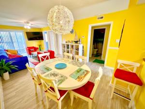 a yellow living room with a table and chairs at Stylish 2BR Condo Near Beach, Large Pool & Patio, Pet Friendly in Rehoboth Beach