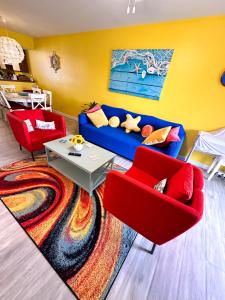 a living room with a blue couch and red chairs at Modern Beachside Bliss: 2 Bed/2 Bath Condo Haven in Rehoboth Beach