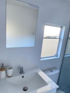 a white bathroom with a sink and a window at Holender Dębki in Dębki