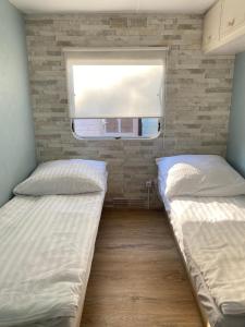 Duas camas num pequeno quarto com uma janela em Holender Dębki em Dębki