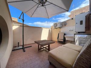 un patio con sombrilla, sofá y mesa en Appartamento in Centro Storico a Termini Imerese - Eden Holiday Home, en Termini Imerese