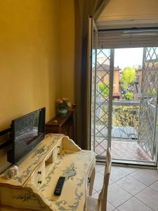 a room with a table and a television and a balcony at Specter Guesthouse in Nettuno