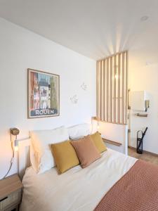 een slaapkamer met een groot wit bed met kussens bij Le Perchoir - Studio vue imprenable - Hypercentre in Rouen