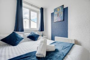 1 cama con almohadas azules y blancas y ventana en Majestic Manc Gem - Pool Table - Parking - Etihad, en Mánchester