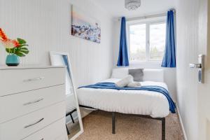 Schlafzimmer mit einem Bett mit blauen Vorhängen und einem Spiegel in der Unterkunft Majestic Manc Gem - Pool Table - Parking - Etihad in Manchester