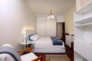 フンシャルにあるRochinha Cozy Homeの白い小さなベッドルーム(ベッド1台、テーブル付)