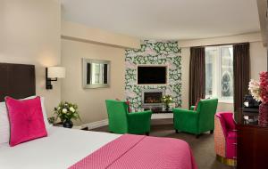 a bedroom with a bed and green chairs and a fireplace at The Ross in Killarney