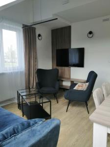 uma sala de estar com um sofá e cadeiras e uma televisão em Rybitwy Residence em Mielno