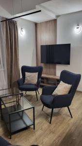 uma sala de estar com duas cadeiras e uma televisão em Rybitwy Residence em Mielno