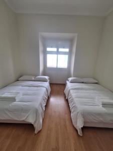 two beds in a white room with a window at Residencial Ideal in Lisbon