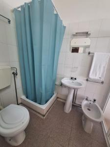 y baño con aseo, lavabo y cortina de ducha azul. en Residencial Ideal, en Lisboa