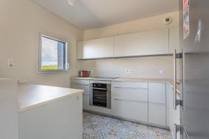 cocina blanca con armarios blancos y ventana en Beautiful T3 with large terrace - Anglet - Welkeys, en Anglet
