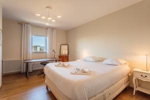 1 dormitorio con 1 cama blanca grande y escritorio en Beautiful T3 with large terrace - Anglet - Welkeys, en Anglet