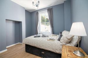 a bedroom with blue walls and a bed with a lamp at SIDNEY in London