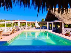 uma piscina num resort com telhado de palha em Hotel Flor de Maria em Puerto Escondido