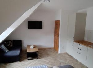 een woonkamer met een bank en een tv aan de muur bij Pokoje Dębowa in Kazimierz Dolny +8 foto's